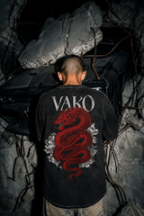 Person wearing a black t-shirt with a red dragon design and 'VARO' branding, standing in a dark, rocky environment.
